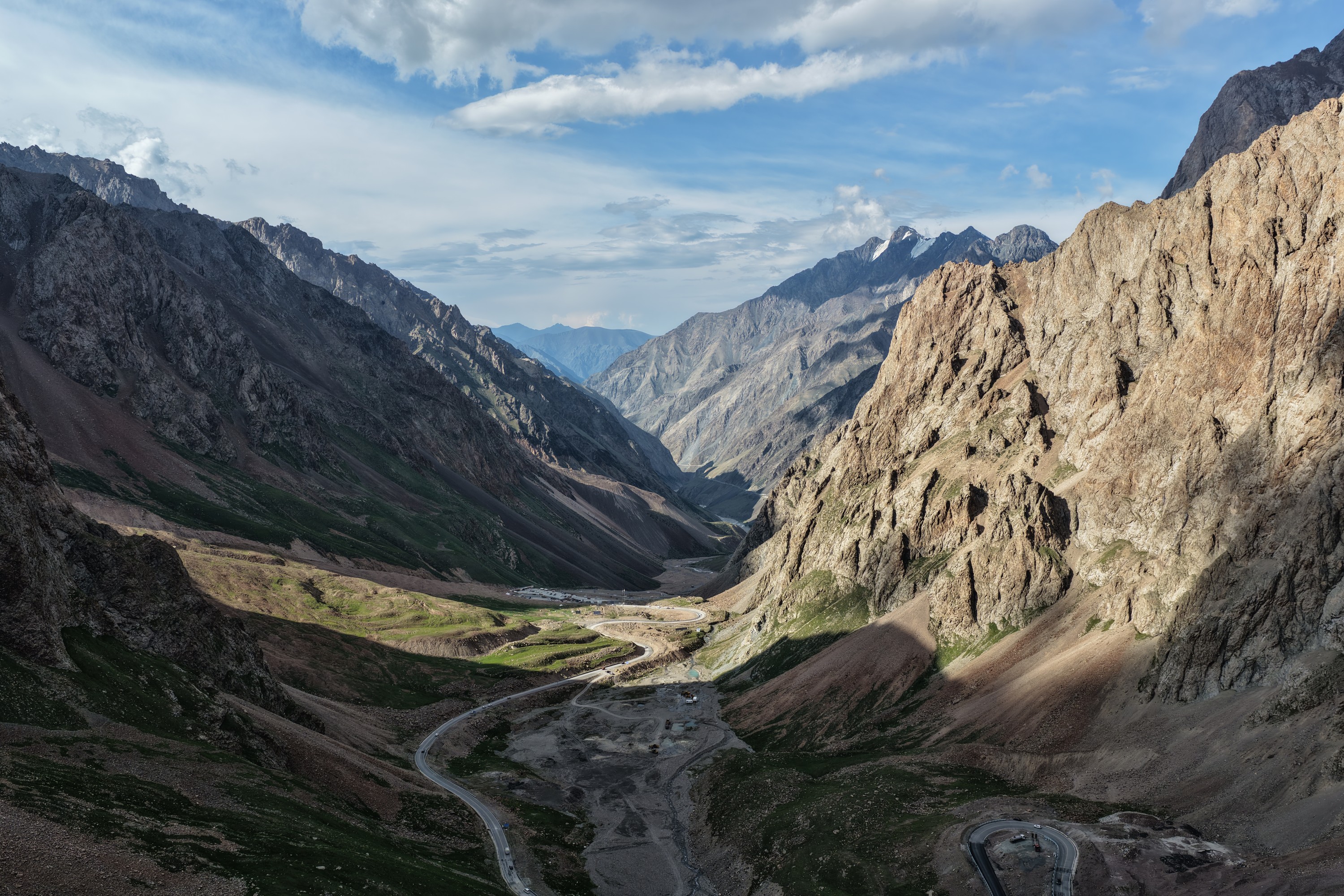 A road curving through a wide green mountain valley